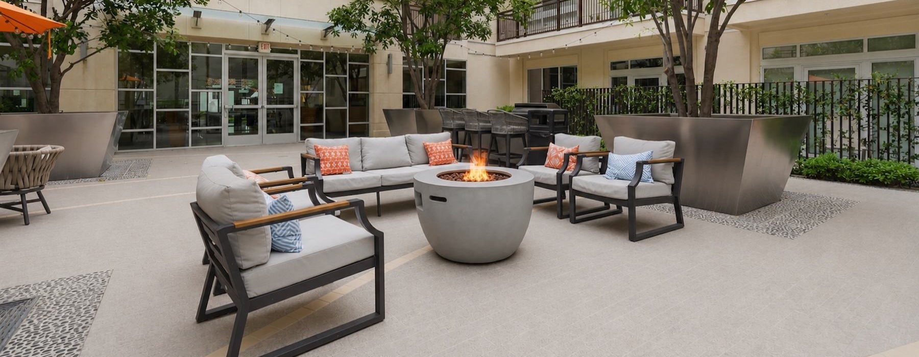 a courtyard with a couch, chairs and a fire pit
